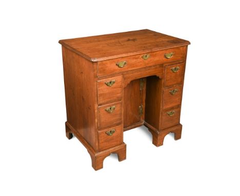 A George III 'red walnut' kneehole desk, with re entrant corners, seven drawers, a blind drawer and central cupboard, brass h