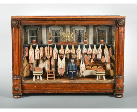 A Victorian butcher`s shop-front model diorama, the painted butcher figure standing to the centre with his display before a f