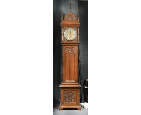 A late Victorian Gothic carved oak chiming longcase clock, the hood with arched pediment having central finial and pinnacles 