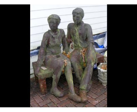 A resign garden ornament of a couple on bench 