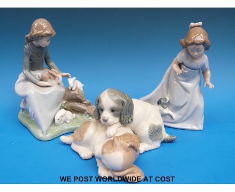 A collection of three Nao figures to include two spaniel puppies, a girl with rabbits and a girl with a puppy