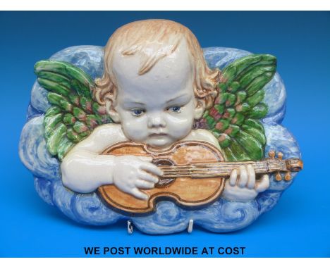 A continental ceramic plaque of a putti playing a guitar (length 27cm)