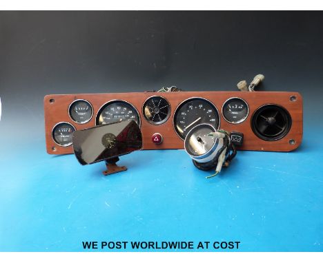 A c1970's TR car dashboard and gauges together with a rear view mirror clock
