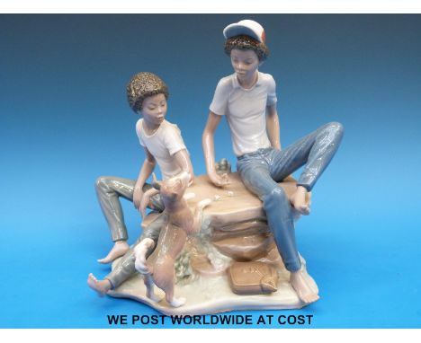 A Lladro figural group of teenagers playing dice with pet dog in attendance (19cm tall) 