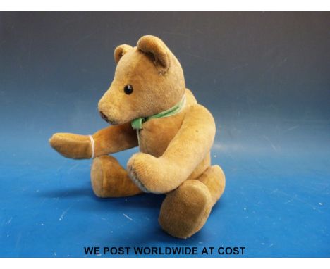 A straw filled teddy bear, possibly Steiff, with cocked hands and wrists, hump back, glass eyes and articulated limbs, 25cm t