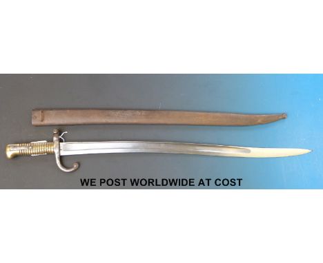 A late 19thC French bayonet in scabbard, D98352 to hilt, with brass handles and curved quillon, 1869 to blade edge 