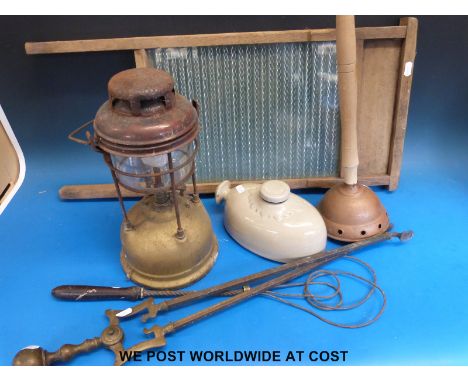 A quantity of kitchenware including a pine and glass washboard, Tilley lamp, carpet beater, fire tongs etc