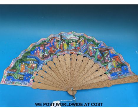 A Chinese fan made up of carved sandalwood and painted paper decorated with court figures with applied fabric clothing and ce
