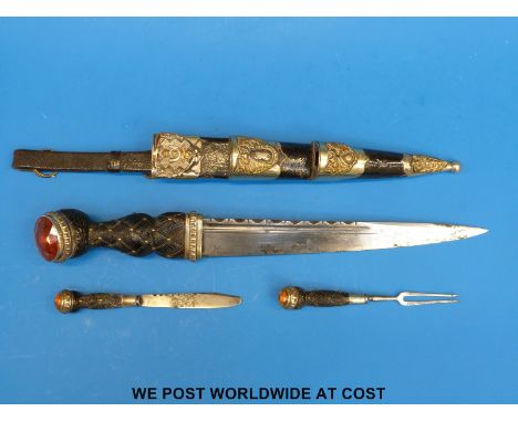 A Scottish regimental dirk with fullered blade in leather scabbard with metal mounts. The grip set with faceted cairngorm sto