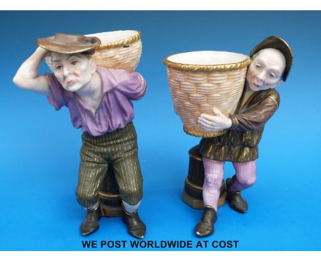 A pair of Royal Worcester figural spill vases or sweetmeat dishes in the form of peasants carrying baskets, puce marks (18cm 