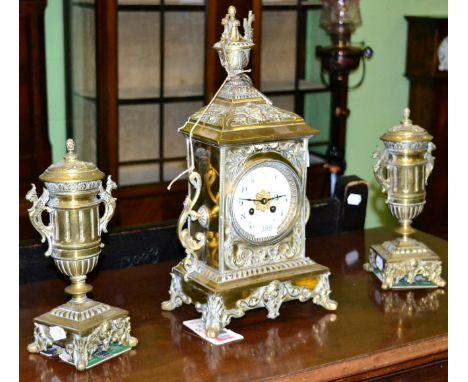 A brass striking mantel clock with garniture, circa 1890