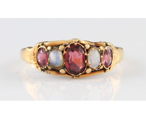 A Victorian style yellow metal pink stone and opal ring, set with three oval cut pink stones, with two replacement opals set 