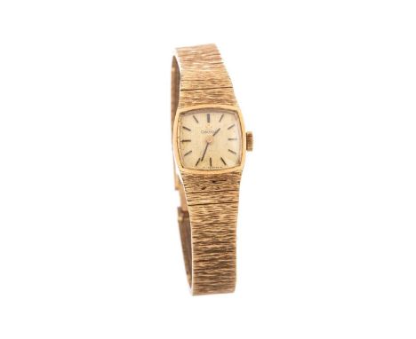 LADY'S OMEGA NINE CARAT GOLD WRIST WATCH,the cushion shaped champagne dial with applied baton hour markers, 15mm case, on a t
