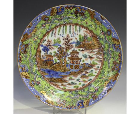 A Chinese 'clobbered' blue and white porcelain circular dish, 18th century and later, painted in underglaze blue with a pagod