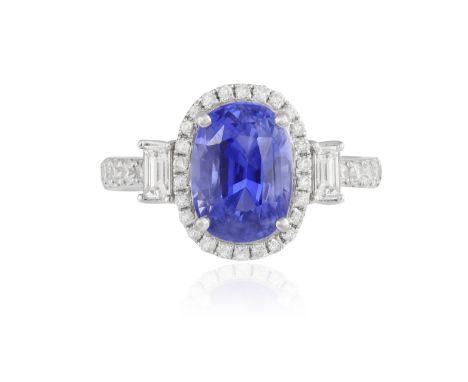 A SAPPHIRE AND DIAMOND RING The oval-shaped sapphire weighing 3.54cts within a brilliant-cut diamond surround, between two re