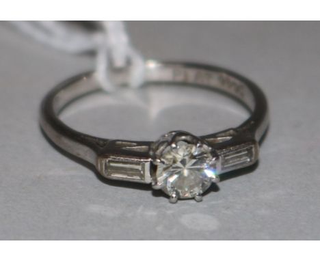 An 18ct white gold and platinum single stone diamond ring with baguette cut diamond set shoulders, size K.