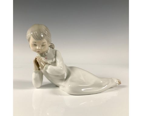 A glossy figure of a young girl in a nightgown laying down, praying before going to bed. Nao by Lladro backstamp. Issued: 198