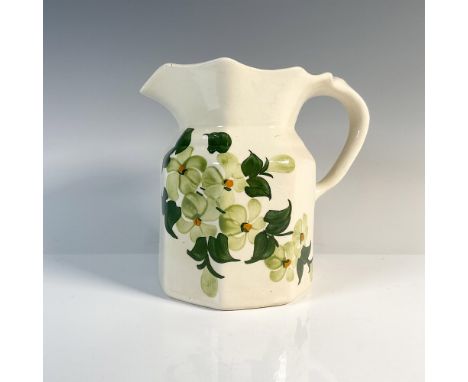 A cream-colored pitcher with a gracefully wavy rim, adorned with exquisite artwork featuring blooming white orchids at its ce