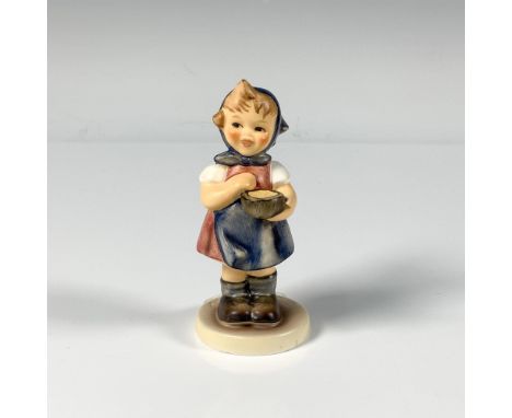 A small hand decorated figure of a smiling young girl in a red dress, blue scarf around her head and she is carrying a basket
