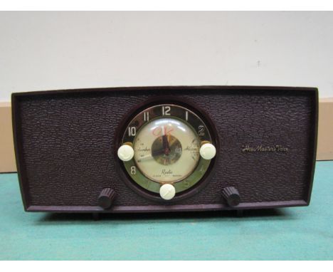 An HMV model 1127 alarm clock radio with socket to switch on bedside lamp or other appliance, housed in maroon thermoplastic 