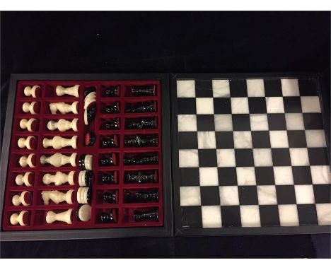 Black and white polished stone chess board with matching chess and draughts pieces. 