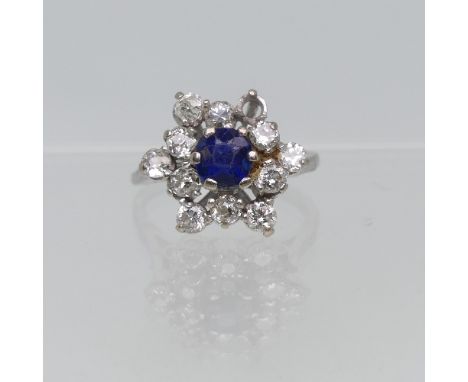 A sapphire and diamond cluster Ring, the central circular facetted sapphire surrounded by eleven diamonds and with one missin