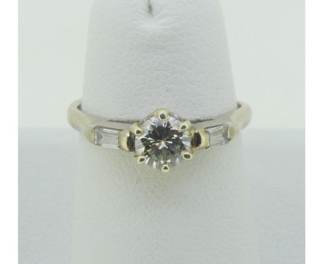 A single stone diamond Ring, the circular cut stone c.0.4ct, with a small baguette diamond on each shoulder, all mounted in 1