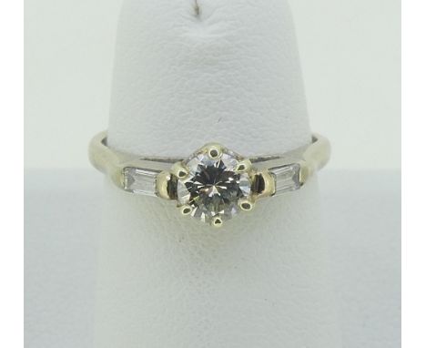 A single stone diamond Ring, the circular cut stone c.0.4ct, with a small baguette diamond on each shoulder, all mounted in 1