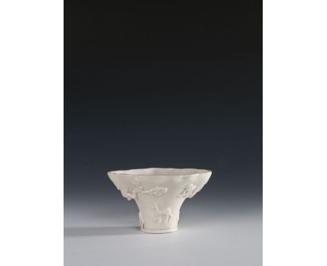 Chinese Blanc de chine porcelain libation cup, Kangxi, the wide top with branches and animals around the body a dragon above 