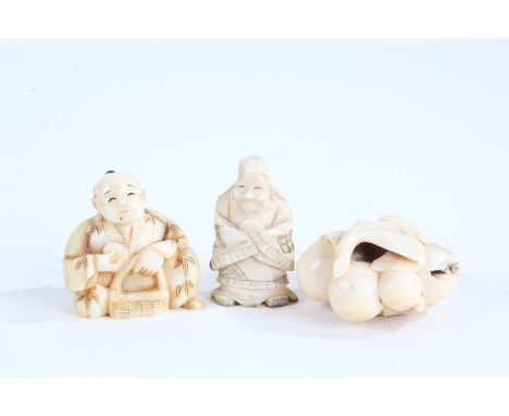 Three Japanese carved ivory netsuke, depicting a seated figure, a standing figure and a small bunch of berries and leaves (3)