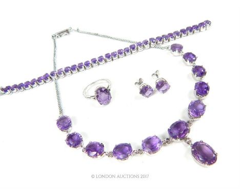 A sterling silver and claw- set purple glass (paste) suite of jewellery to include a pair of stud earrings, a ring (Size M 1/