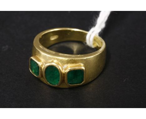 A three stone emerald tapered gold band ring, marked 750