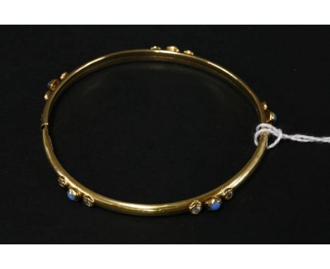 A blue glass and cubic zirconia set gold bangle, tested as approximately 14ct gold