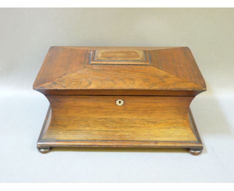 A 19th century rosewood tea caddy, in the sarcophagus form, turned handles and bun feet