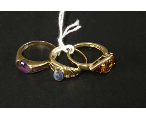 A 9ct gold citrine and garnet three stone ring, an opal triplet ring marked 18k, and a 9ct gold amethyst ring