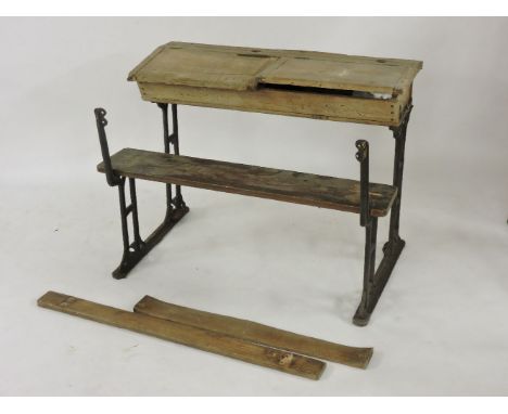 An early 20th century school double desk, and incorporated bench on cast iron legs