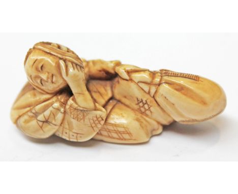 A 19th Century Japanese ivory netsuke formed as a figure head in one hand and bag in the other, two character signature to ba