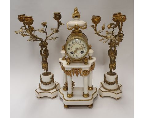 A late 19th Century French eight day mantel clock in the Empire style, flanked by a similar pair of garniture candle holders 