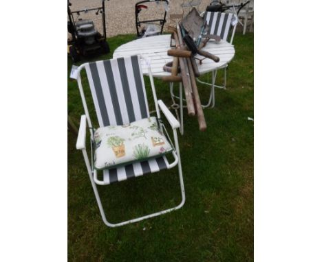 A painted slatted wooden garden table of circular form raised on a metal base together with a pair of folding chairs and a co