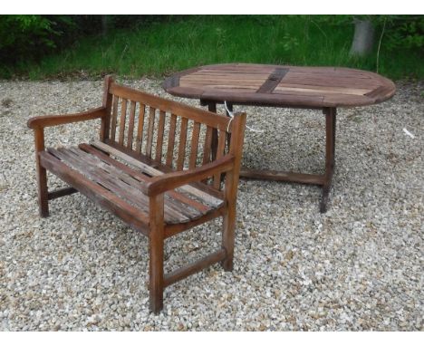 A stained slatted teak bench and similar garden table 