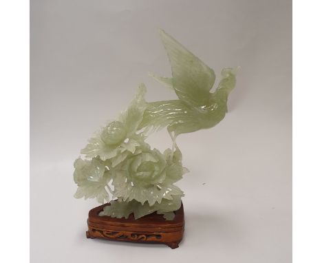 A 20th Century carved jade figure of a phoenix amongst flowers on a carved wooden stand