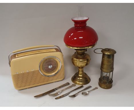 A brass miner's lamp by E Thomas and Williams Limited of Aberdare, a brass oil lamp with red glass shade, a Bush type TR82D b