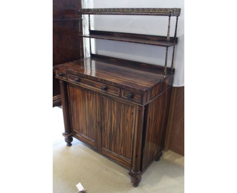 A late Regency coromandel and gilt brass embellished chiffonier, the three quarter galleried open two tier shelf unit on balu