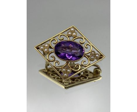 A Victorian 15ct gold lozenge shaped brooch, having a central, oval amethyst 11 x 7.5mm, surrounded by pierced, scroll design