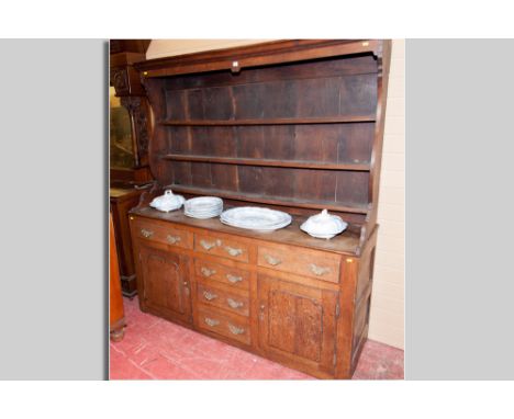 A late 18th Century flat fronted oak Welsh dresser, the three shelf rack with shaped sides (pot belly), the base with a twin 