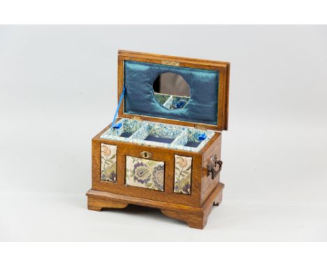 An Edwardian oak jewellery chest with metal carrying handles on bracket corner feet, the sarcophagus shaped lid opening to re