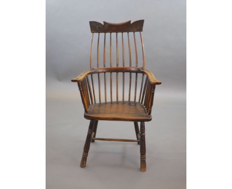   A primitive comb back Windsor armchair, possibly West Country,with a shaped rail above a notch-cut back, swept arms and tur