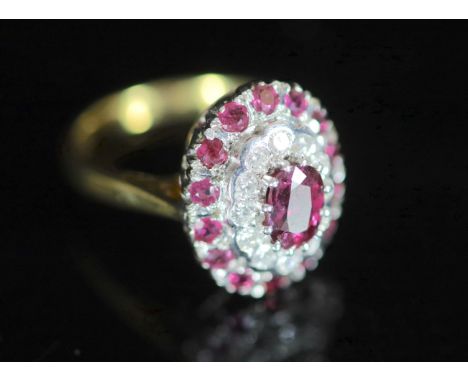  A modern 18ct gold, ruby and diamond set oval cluster ring,with central oval cut ruby, bordered with concentric bands of di