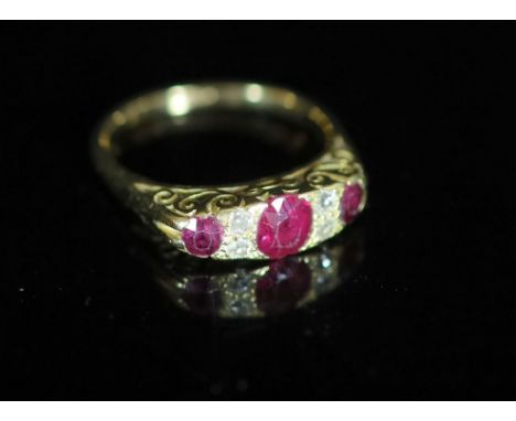   An early 20th century 18ct gold, three stone ruby and four stone diamond chip set half hoop ring,with carved setting, size 