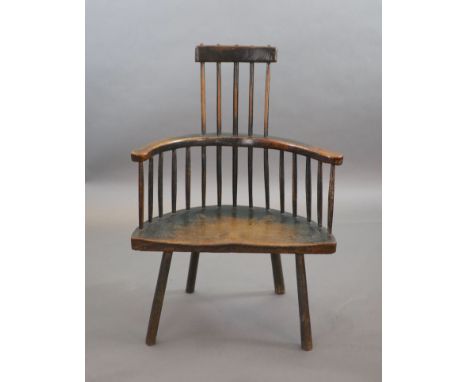   An 18th century primitive vernacular comb-back elbow chair, possibly Welsh,with remnants of original painted finish.70cm wi